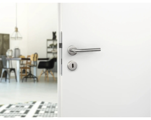 Geopende witte deur met zilverkleurige deurklink en uitzicht op een lichte kamer