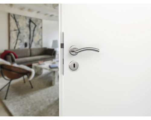 Openstaande witte deur met zilverkleurige deurkruk en zicht op een woonkamer