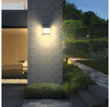 Vierkante wandlamp aan een bakstenen muur in de tuin