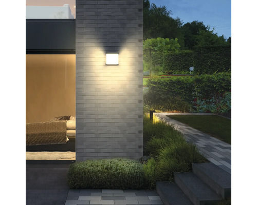 Vierkante wandlamp aan een bakstenen muur in de tuin