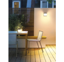 Buitenruimte met houten terras, tafel, stoelen, wandlamp en tafellamp