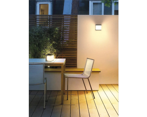 Buitenruimte met houten terras, tafel, stoelen, wandlamp en tafellamp