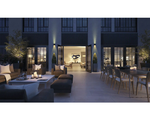 Groot terras met zithoek, eettafel en decoratie in de avond.