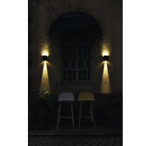 Exterieur van een gebouw met twee barkrukken onder een raam met twee wandlampen.