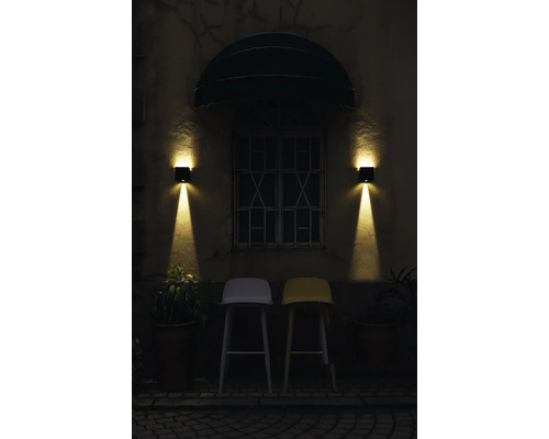 Exterieur van een gebouw met twee barkrukken onder een raam met twee wandlampen.