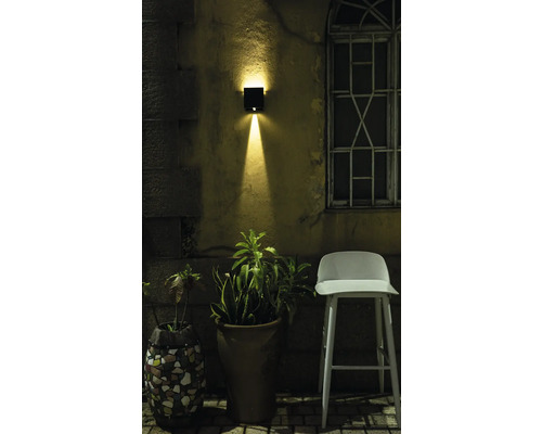 Scene met buitenmuurlamp, bloempotten en stoel in de tuin