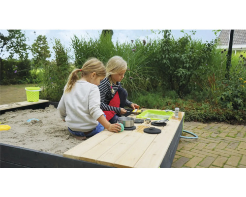 Twee kinderen spelen in een zandbak met speelkeuken in de tuin.