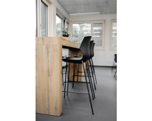 Scene met statafel en zwarte barkrukken in een lichte ruimte.