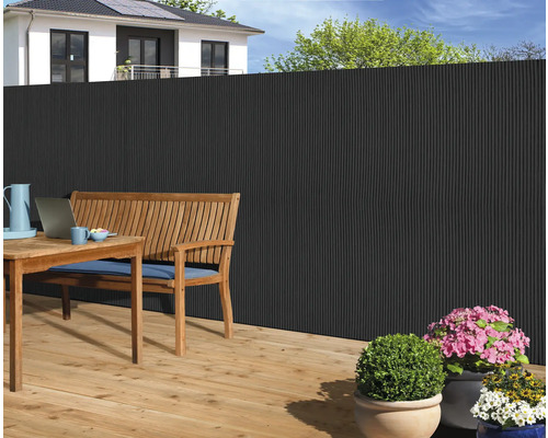 Tuinscene met privacy schutting, houten tafel en bank