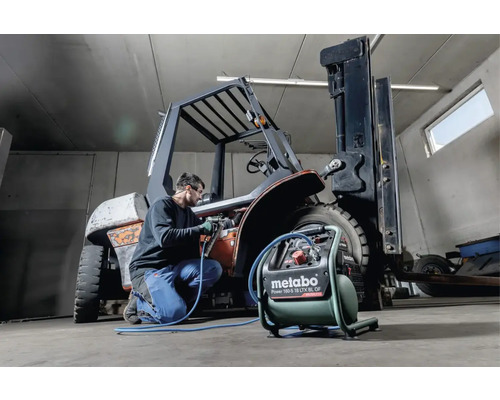 Man werkt met een Metabo compressor aan een vorkheftruck in een werkplaats.
