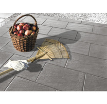 Bestrating op een terras met een mand vol appels, een hark en tuinhandschoenen