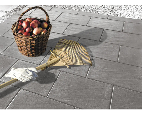 Bestrating op een terras met een mand vol appels, een hark en tuinhandschoenen