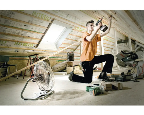 Ambachtsman bezig met dakrenovatie met gereedschap zoals een accuboormachine, ventilator en bouwradio.