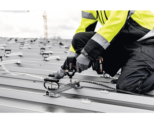 Een vakman monteert met een Metabo accuslagschroevendraaier een zonnepaneel op een dak.