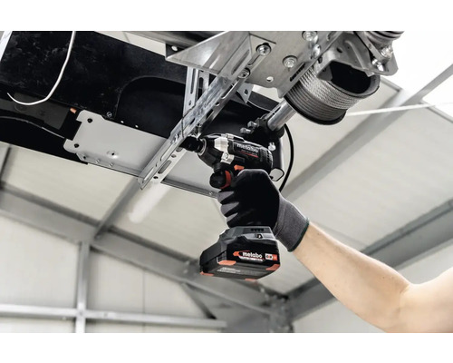 Ambachtsman monteert een garagedeurinrichting met een Metabo accuslagschroevendraaier