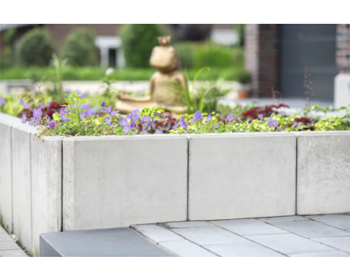 Betonnen plantenbak met planten en decoratie in de tuin.