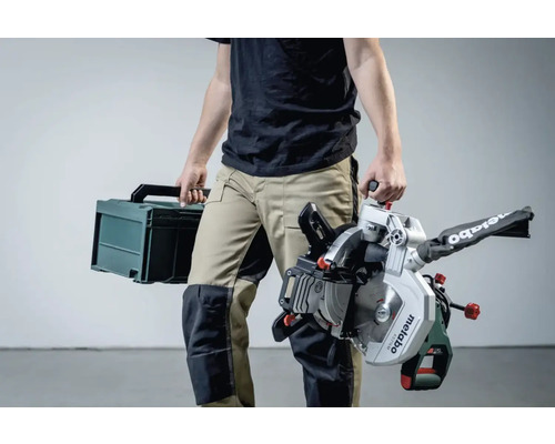 Een persoon draagt een Metabo verstekzaag en een gereedschapskoffer.