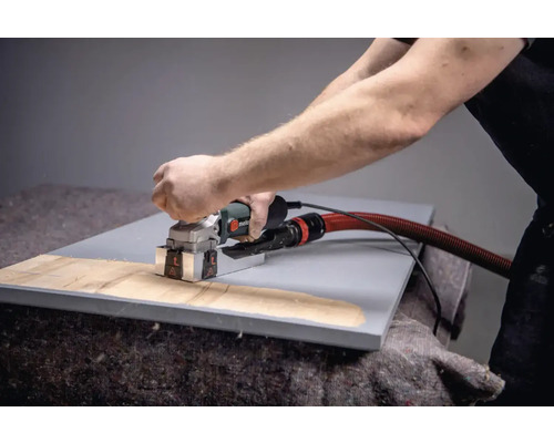 Een persoon gebruikt een muurfrees op een werkstuk.
