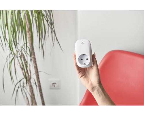 Een hand houdt een wit slim stopcontact vast.