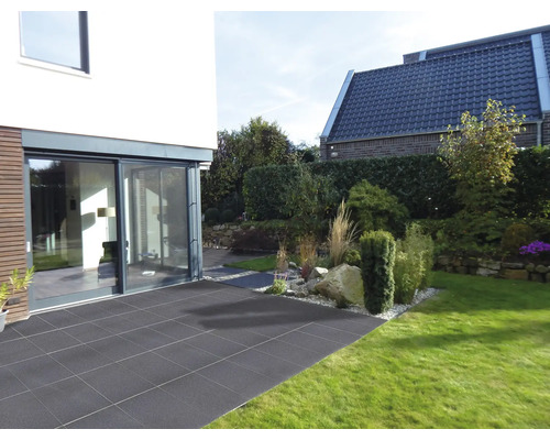 Tuin met terras van stenen tegels, grenzend aan een modern woonhuis