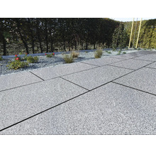 Terras met grijze stenen tegels en grindbed met planten