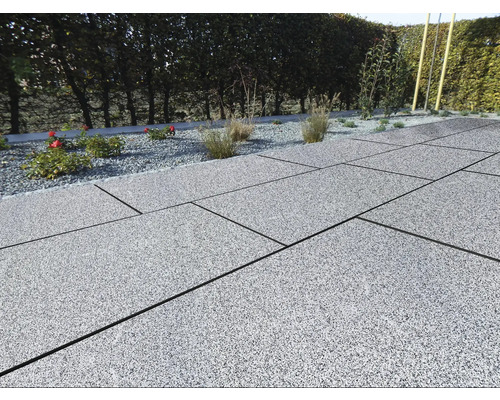 Terras met grijze stenen tegels en grindbed met planten