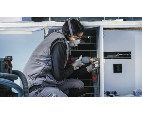 Een vakvrouw werkt met een multifunctioneel gereedschap aan een badkamerkast.