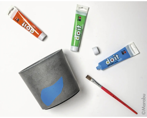 Betonnen bloempot met verf, penseel en tubes verf