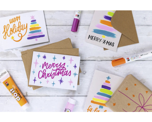 Kerstkaarten met kerstmotieven en kleuren, omringd door knutselspullen zoals stiften en verf