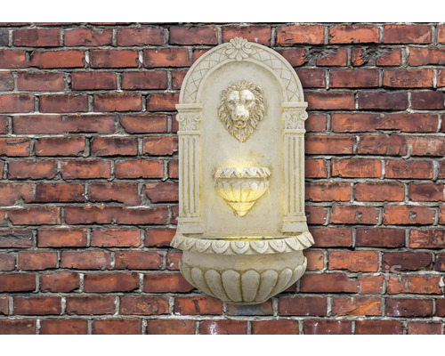 Muurfontein met leeuwenkop en verlichting voor een bakstenen muur