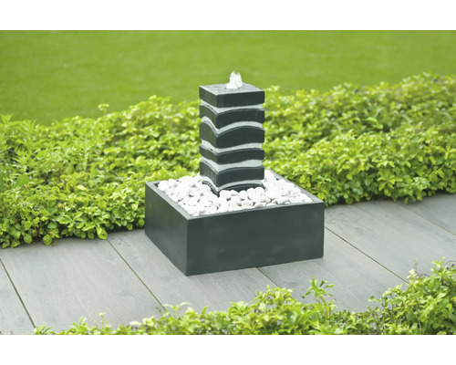 Decoratieve tuinfontein met waterspel en witte stenen