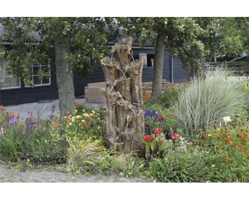 Tuin met decoratieve boomstamfontein en bloemen