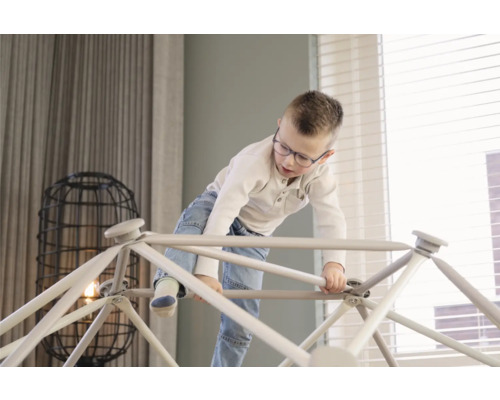 Jonge klimt op indoor klimrek in woonkamer