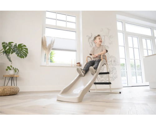 Een kind zit op een glijbaan in een lichte kamer