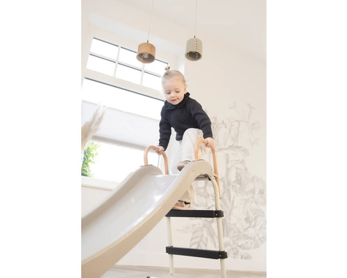 Peuter klimt op een glijbaan binnenshuis.