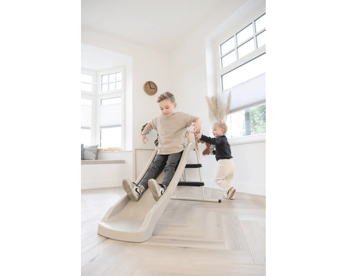 Twee kinderen spelen in de lichte woonkamer met een kindglijbaan met ladder.