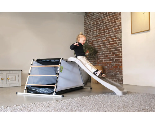 Peuter glijdt van speelplaatstglijbaan met klimrek binnenshuis