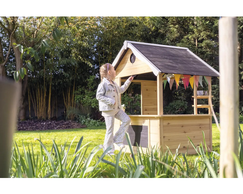 Meisje voor speelhuis van hout in de tuin.