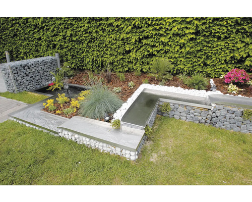 Tuinscene met schanskorfmuur, vijver en diverse planten.