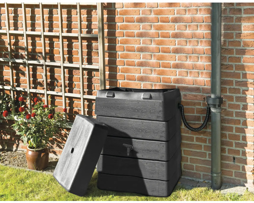 Regenton van kunststof met open deksel naast een huismuur.