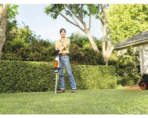 Vrouw met accu heggenschaar in de tuin voor een haag.