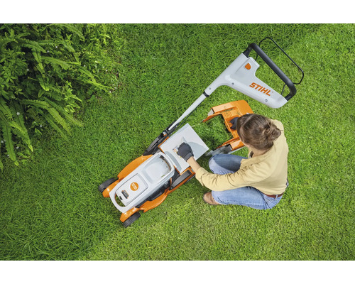 Bovenaanzicht van een vrouw die een gazonmaaier voorbereidt op een gazon. Stihl logo.