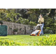 Vrouw bedient gazonmaaier in de tuin