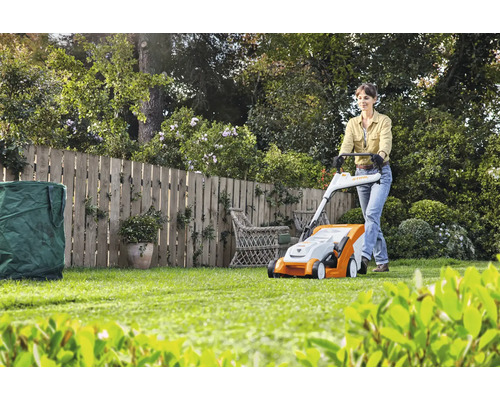 Vrouw bedient gazonmaaier in de tuin