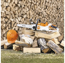 Accukettingzaag met veiligheidshelm, veiligheidsbril en handschoenen op een stapel hout