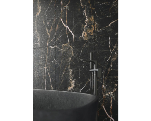 Badkamerwand met tegels in marmerlook, gecombineerd met een vrijstaand bad en kraan