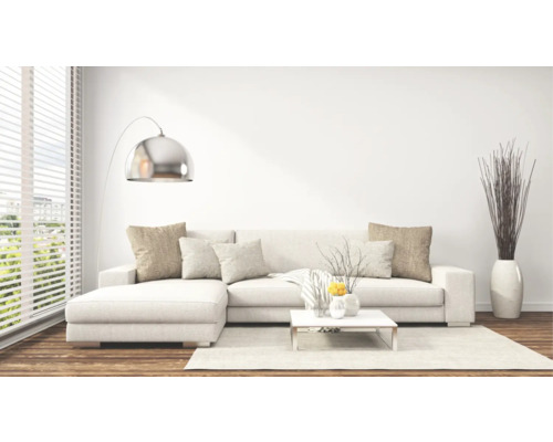 Lichte woonkamer scène met hoekbank, staande lamp en decoratieve elementen.