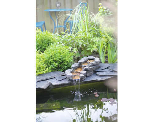 Vijver in de tuin met stenen waterval en vijverplanten