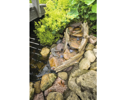 Tuinfontein met waterval, boomstamontwerp en verlichting in de buurt van de vijver