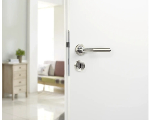 Witte binnendeur met roestvrijstalen deurbeslag in een lichte kamer